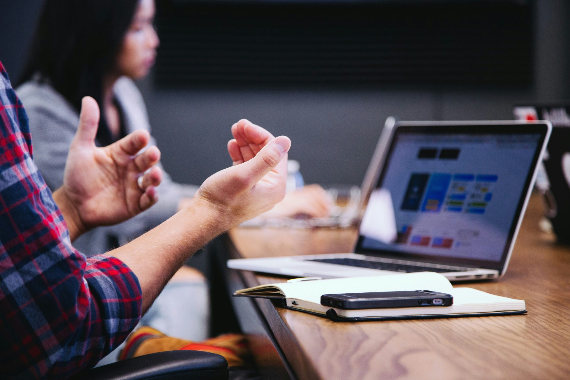 person gesturing during meeting with laptop
